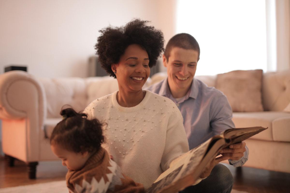 imagem de uma família sentada, sorrindo e lendo um livro todos juntos